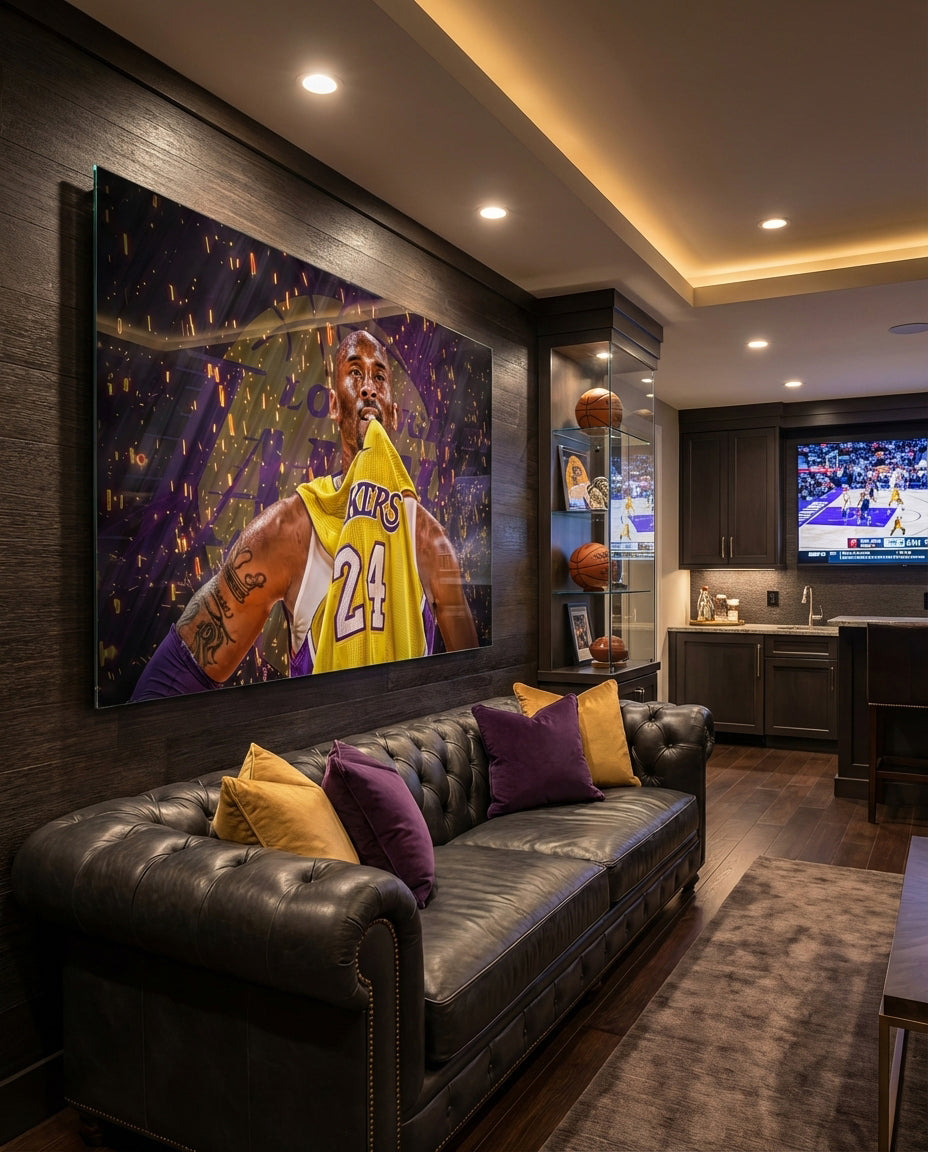 Kobe Bryant glass wall art displayed above a black tufted leather sofa in a man cave with basketball shelf and brushed-brass sconces