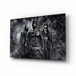 Batman, Catwomen and Bane glass wall art displayed above a black leather sectional in a moody home theater with brass arc lamp and reclaimed-wood console