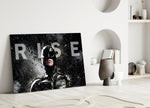 Batman Rise close-up showing Dark Knight cowl with monumental RISE wordmark in sleet