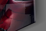 Close-up detail of the black symbiote fangs and red spider mask behind glass