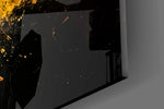 Close-up detail of the yellow drip and splatter on black surface behind glass