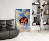 an eye and hand breaking through a painted sky glass wall art leaning beside a dark leather sofa