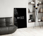 interlocking rich and risk typography glass wall art leaning beside a dark leather sofa