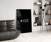 interlocking rich and risk typography glass wall art leaning beside a dark leather sofa