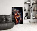 a hand of smoke and fire cradling planet earth glass wall art leaning beside a dark leather sofa