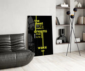 wake up dreams quote in yellow glass wall art leaning beside a dark leather sofa