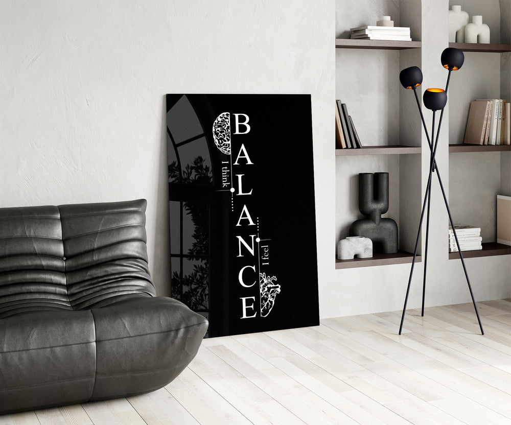 balance brain and heart quote glass wall art leaning beside a dark leather sofa