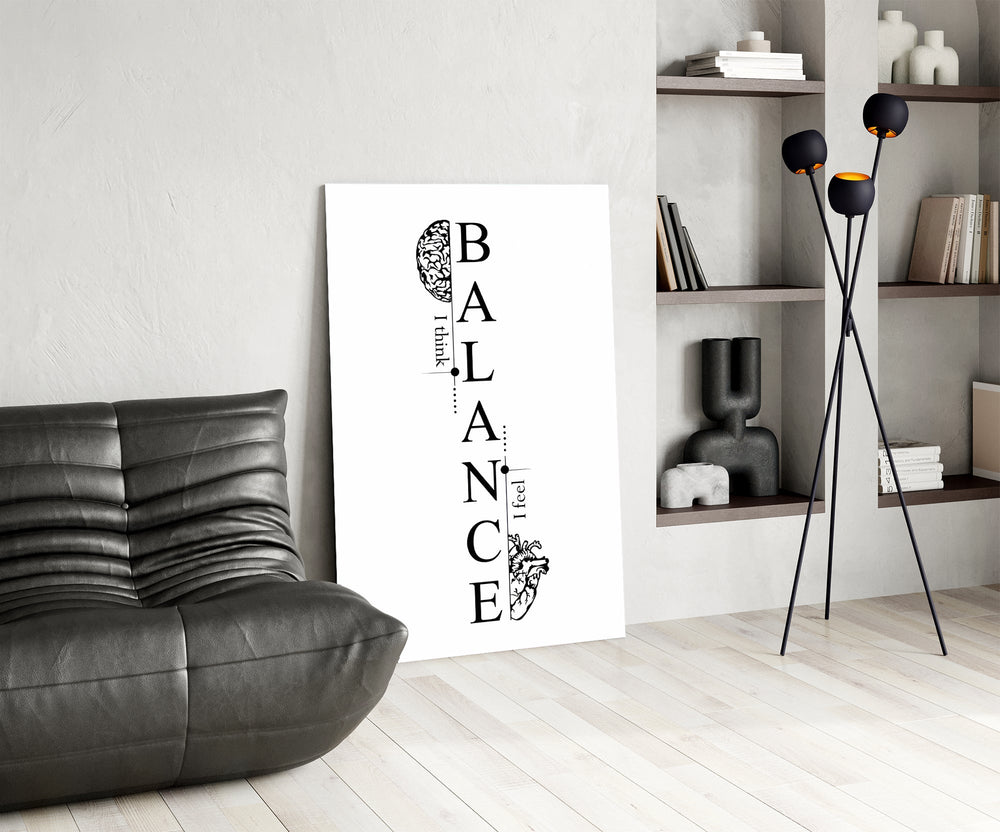 balance brain and heart typography glass wall art leaning beside a dark leather sofa