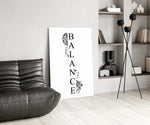 balance brain and heart typography glass wall art leaning beside a dark leather sofa