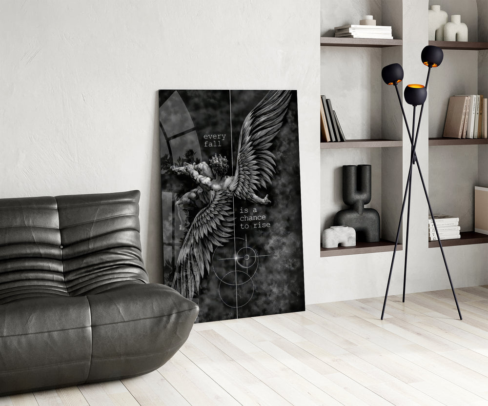 winged figure every fall to rise glass wall art leaning beside a dark leather sofa
