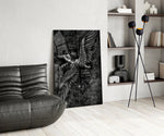 winged figure every fall to rise glass wall art leaning beside a dark leather sofa