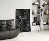 winged figure every fall to rise glass wall art leaning beside a dark leather sofa