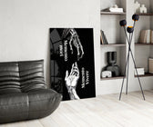 skeletal and living hands memento mori glass wall art leaning beside a dark leather sofa