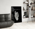 a skeleton hand gripping a roll of cash glass wall art leaning beside a dark leather sofa