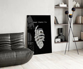a skeleton hand gripping a roll of cash glass wall art leaning beside a dark leather sofa