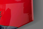 Close-up detail of the red mirrored lenses and the row of steel spikes at the throat on the glass surface