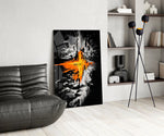 orange lava rift and lone figure glass wall art leaning beside a dark leather sofa