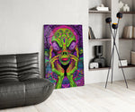 neon green alien face among mushrooms glass wall art leaning beside a dark leather sofa
