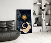a gold sun and crescent moon on navy glass wall art leaning beside a dark leather sofa