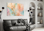 translucent peach and mint petals in gold glass wall art styled above an armchair in a reading corner