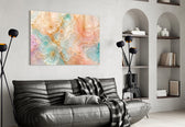 translucent peach and mint petals in gold glass wall art styled above an armchair in a reading corner