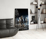 a herd of horses galloping through a storm glass wall art leaning beside a dark leather sofa