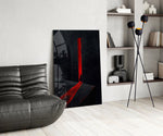 a cloaked figure at a red doorway glass wall art leaning beside a dark leather sofa