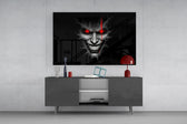 cracked gray grinning demon face glass wall art displayed above a console in a designer interior