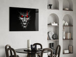 cracked gray grinning demon face glass wall art leaning beside a dark leather sofa