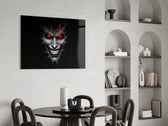 cracked gray grinning demon face glass wall art leaning beside a dark leather sofa