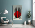 crimson sun behind bare poplars glass wall art styled above an armchair in a reading corner