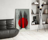 crimson sun behind bare poplars glass wall art leaning beside a dark leather sofa
