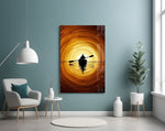 a lone kayaker at golden sunset glass wall art styled above an armchair in a reading corner
