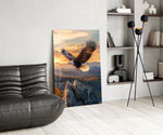 a bald eagle over autumn mountains at sunset glass wall art leaning beside a dark leather sofa