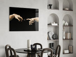 two reaching hands with a loading spinner glass wall art leaning beside a dark leather sofa