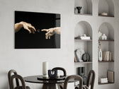 two reaching hands with a loading spinner glass wall art leaning beside a dark leather sofa