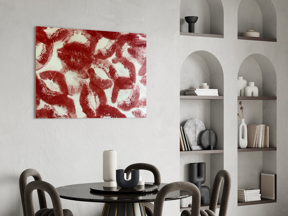 red lipstick kiss prints glass wall art leaning beside a dark leather sofa