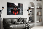 open-wheel race car from behind on a wet track glass wall art styled above an armchair in a reading corner