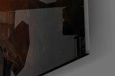Close-up detail of the outstretched fingers catching the shaft of light on the glass surface