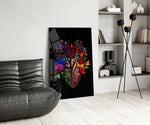 floral anatomical heart glass wall art leaning beside a dark leather sofa