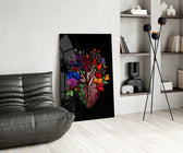 floral anatomical heart glass wall art leaning beside a dark leather sofa