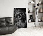 vintage blonde bombshell portrait glass wall art leaning beside a dark leather sofa