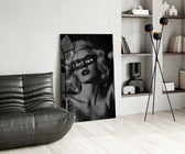 vintage blonde bombshell portrait glass wall art leaning beside a dark leather sofa
