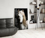white horse portrait on black glass wall art leaning beside a dark leather sofa