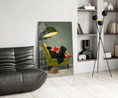 woman reading in a green armchair glass wall art leaning beside a dark leather sofa