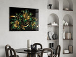emerald and gold lilies on black glass wall art leaning beside a dark leather sofa