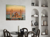 golden sunset six-minaret mosque glass wall art leaning beside a dark leather sofa