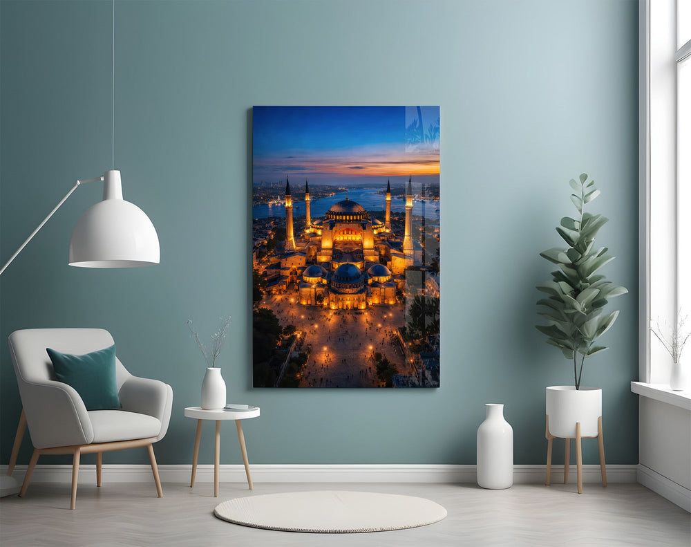 twilight aerial view of an illuminated mosque glass wall art styled above an armchair in a reading corner