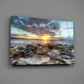 Close-up detail of rocky shoreline meeting dramatic sunset clouds