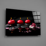 Close-up detail of red candles, black stones, and orchid in still reflection